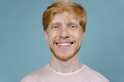 Portrait of a happy redhead man smiling against a blue background in a studio shoot.