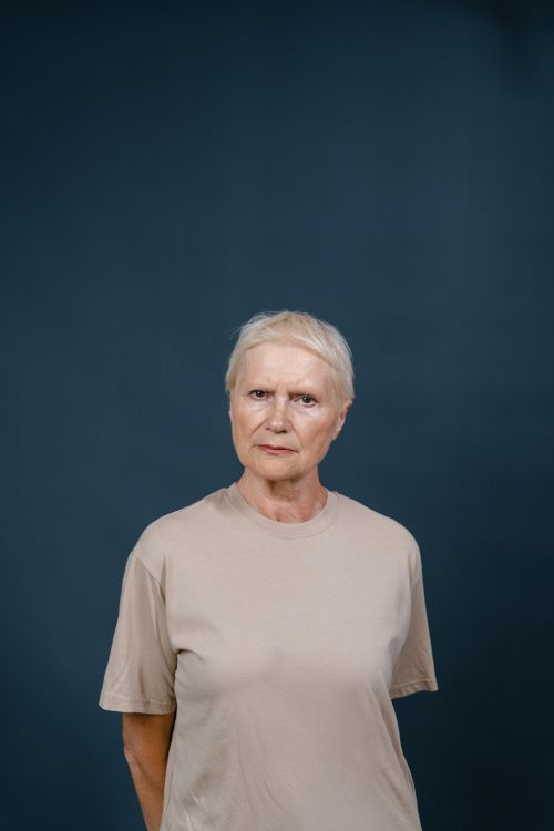 Free Elderly woman in a beige shirt showing a skeptical expression in a studio portrait. Stock Photo