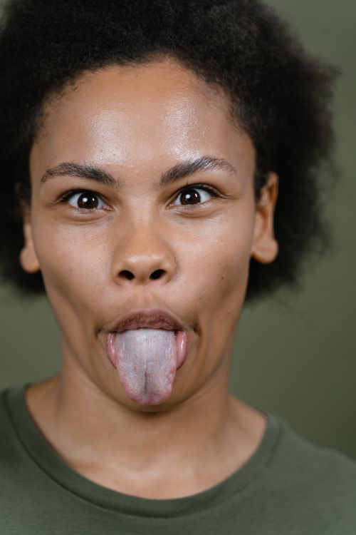 Free A playful woman making a silly face with her tongue out against a green background. Stock Photo
