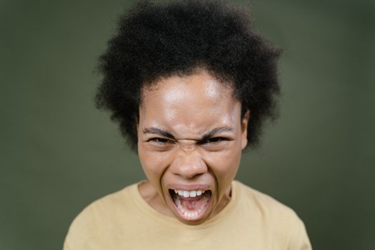 Close-up of an African American woman with afro hair expressing anger in a studio setting.
