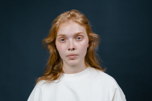 Free Studio portrait of a young woman with red hair and a neutral expression. Stock Photo