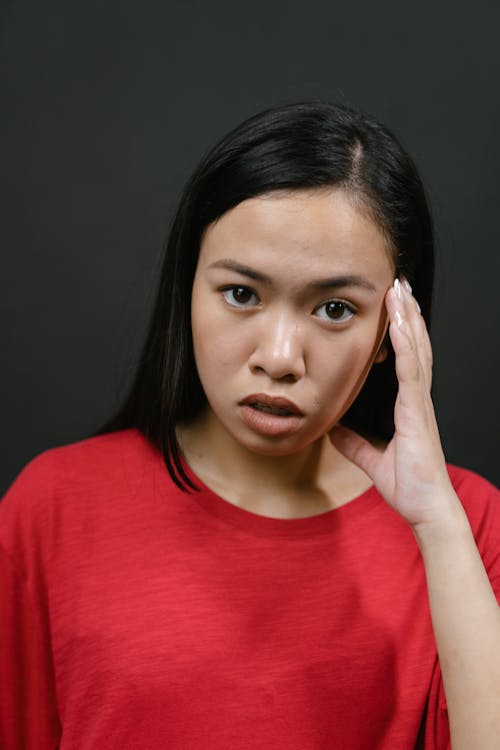 Woman in Red T-Shirt Touching Head