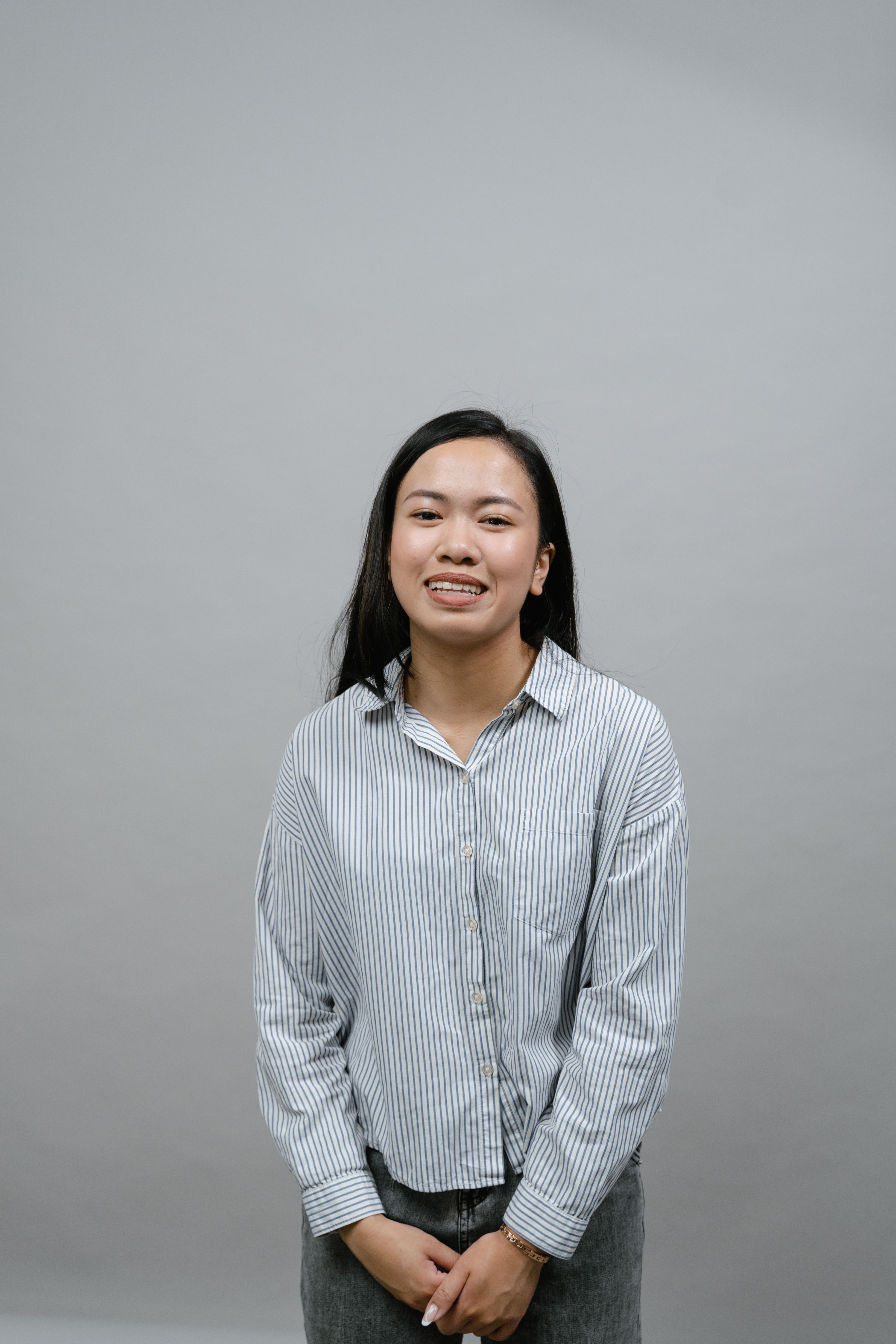 Portrait of a smiling woman in a striped shirt, captured in a studio setting.