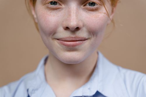 Free A smiling redhead girl with freckles captured in a warm, close-up portrait. Stock Photo