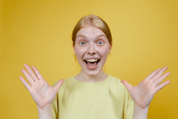 Smiling Woman In Yellow T-shirt Holding Hands Apart