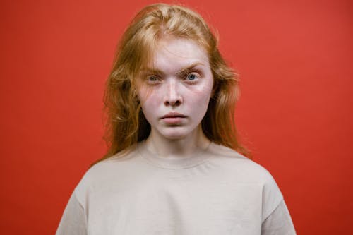 Angry Woman in Beige T-Shirt Near Red Background