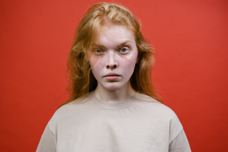 Angry Woman In Beige T-Shirt Near Red Background