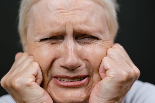 Portrait of Elderly Woman Crying with Face on Fists