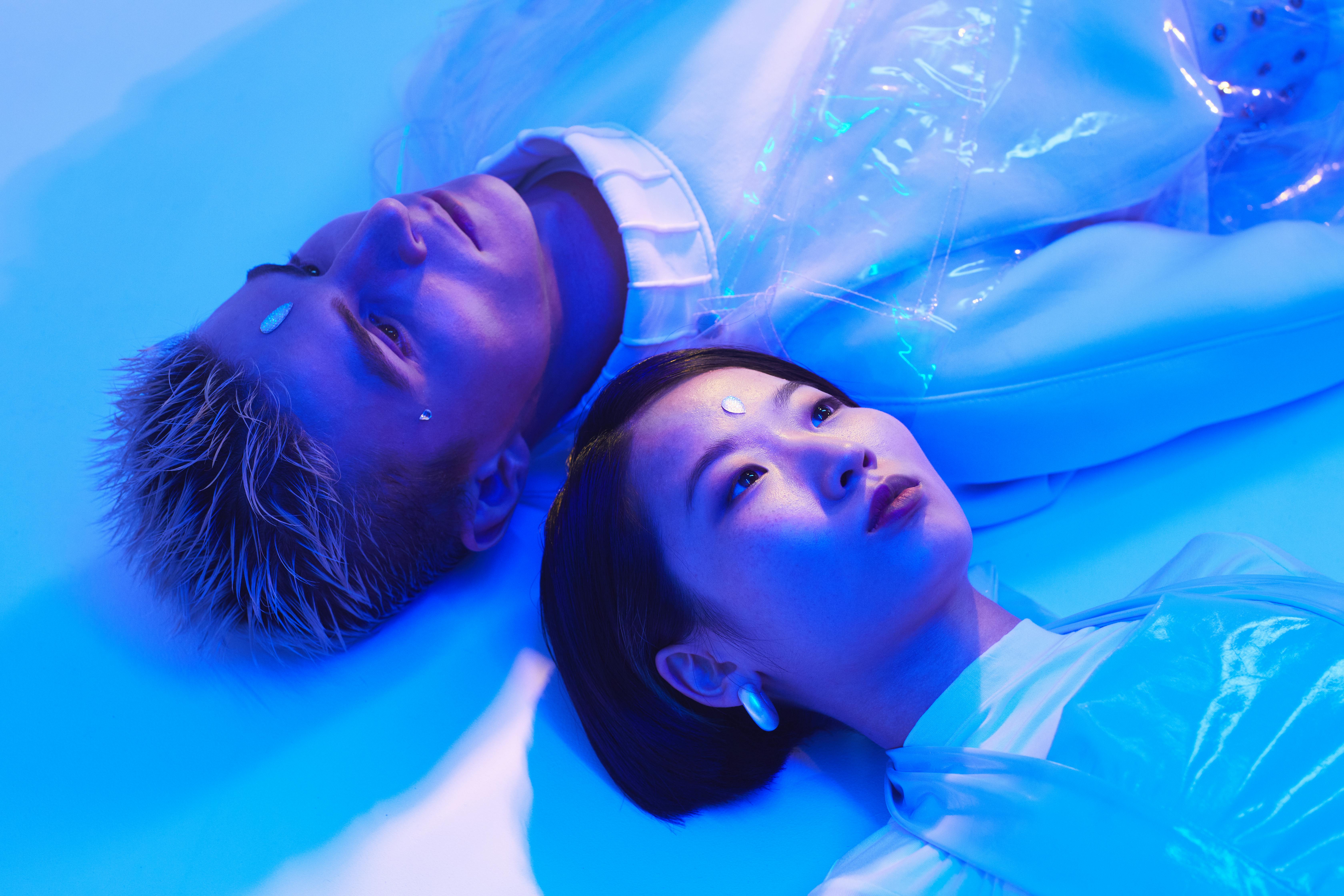 futuristic photo of a young man and woman lying on the floor in blue lighting