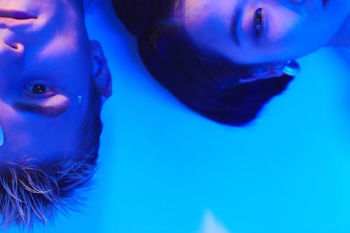 Futuristic Photo of a Young Man and Woman Lying on the Floor in Blue Lighting 