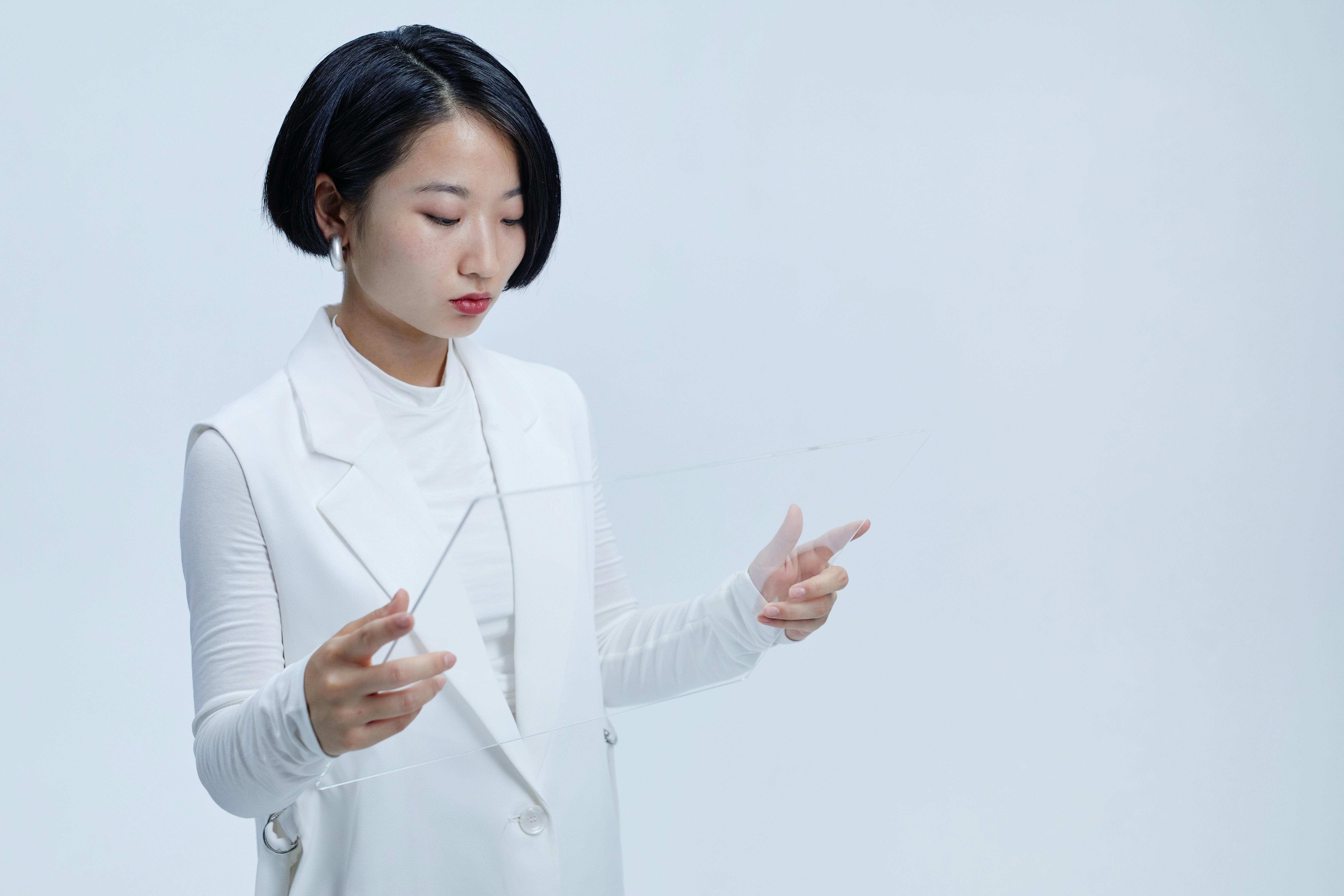 young woman in white long sleeve shirt holding transparent glass