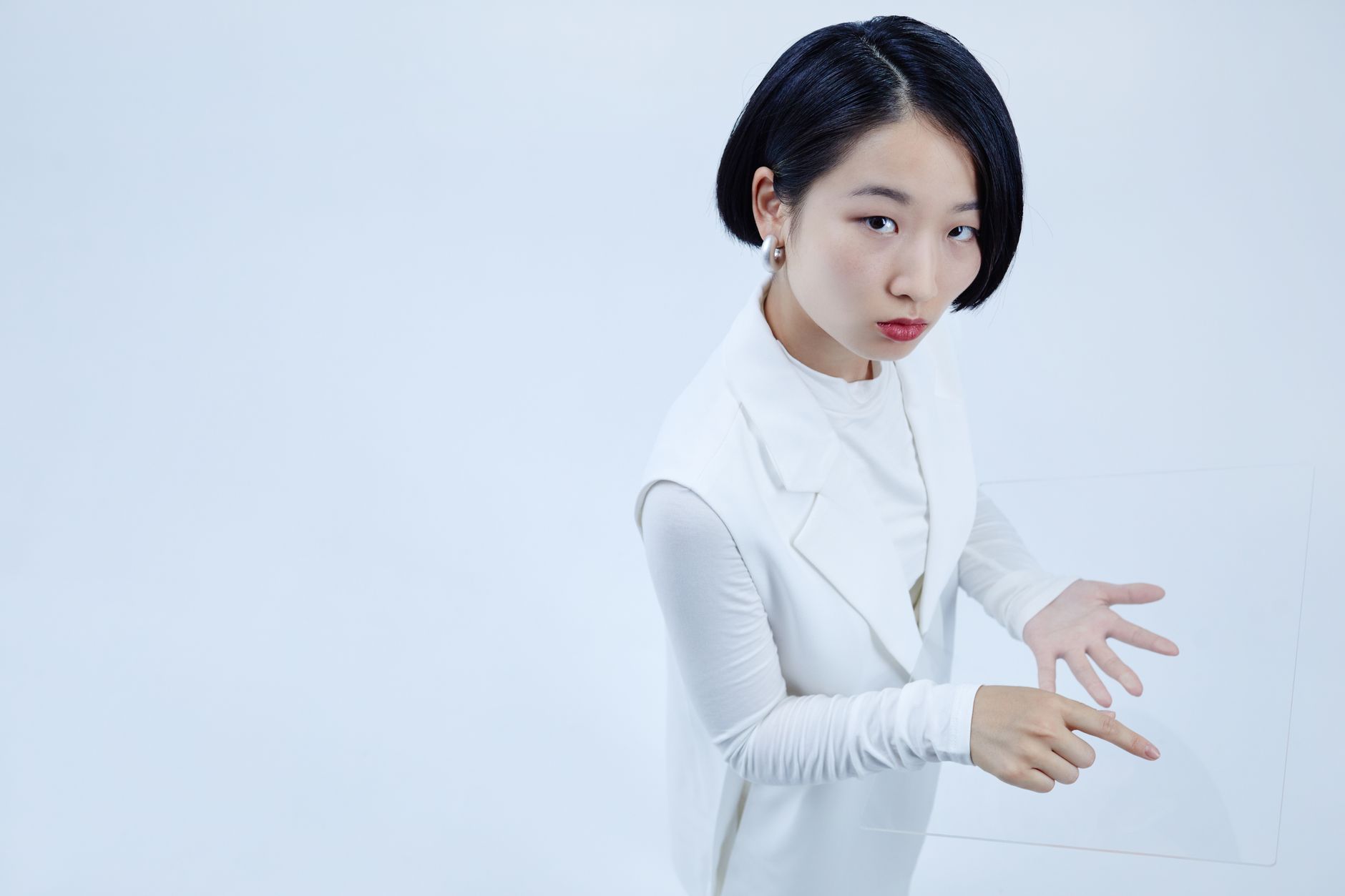 Asian woman interacting with transparent tablet in conceptual high angle view.