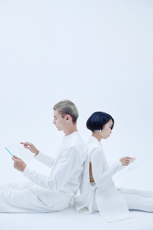 Man and Woman in White Clothes Sitting Back to Back 