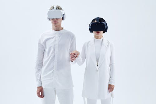 A Man and Woman Holding Hands while Wearing Virtual Reality Goggles