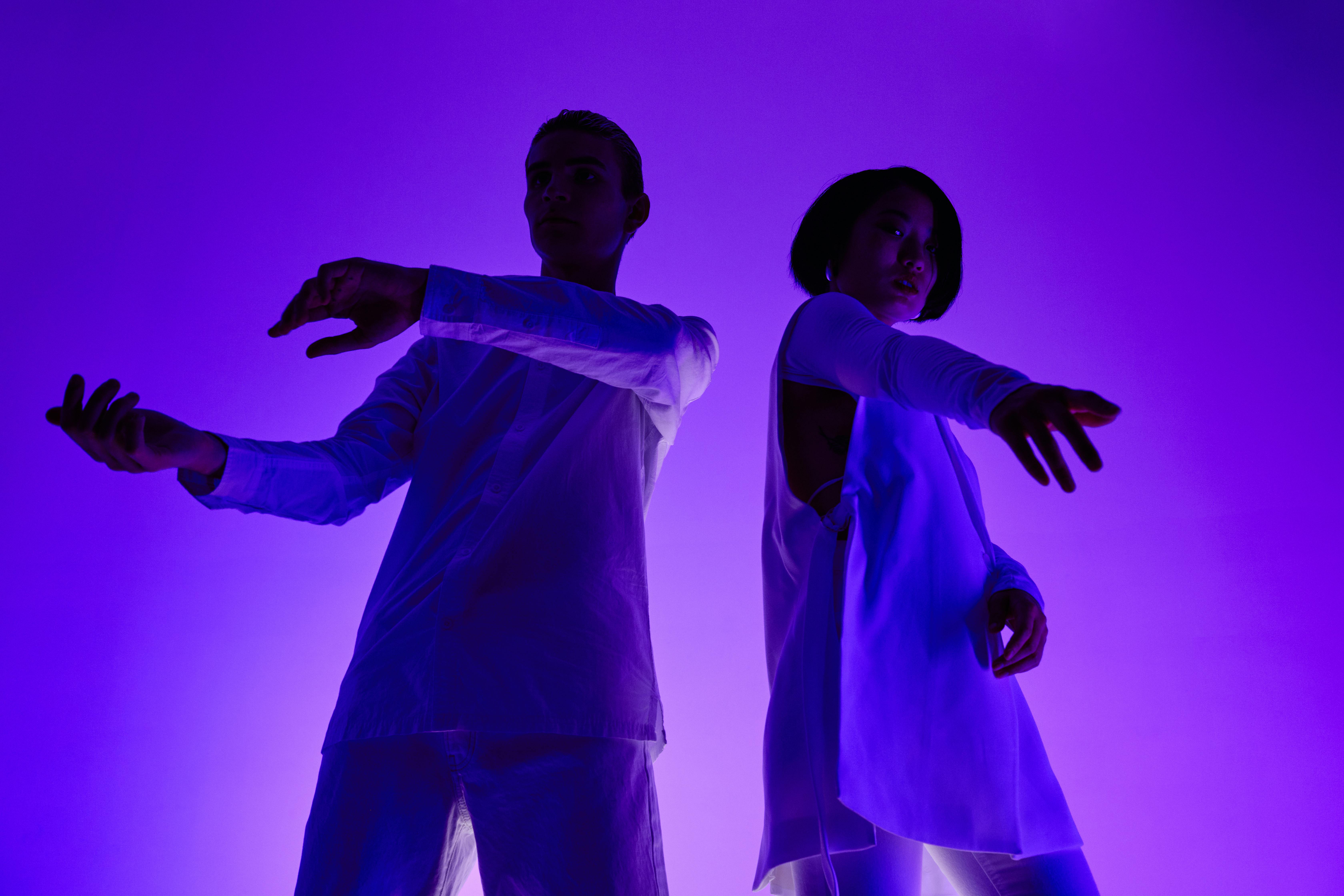 Free Two dancers performing under striking blue and purple lighting with dynamic hand movements. Stock Photo