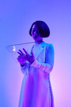 Stylish Asian woman in futuristic attire with vibrant blue and purple lighting holding a transparent device.