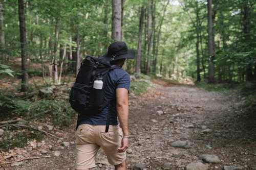 Man in Hat with Backpack Walking Up the Hill