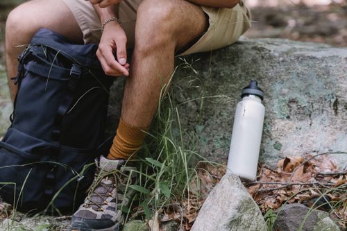 Free Close-up of a hiker with gear, resting on a stone outdoors. Stock Photo