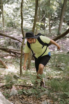 A man in casual attire hikes through a sunny forest, emphasizing adventure.