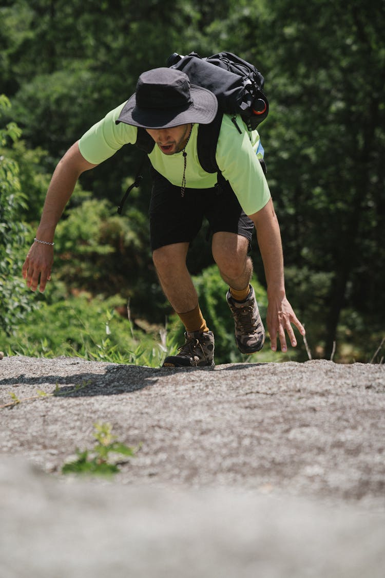 Man With Black Hat Climbing On Rock