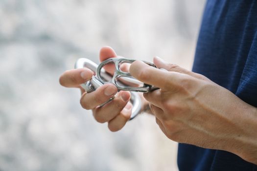 A detailed close-up photo of hands holding shiny metal carabiners, ideal for outdoor activities.