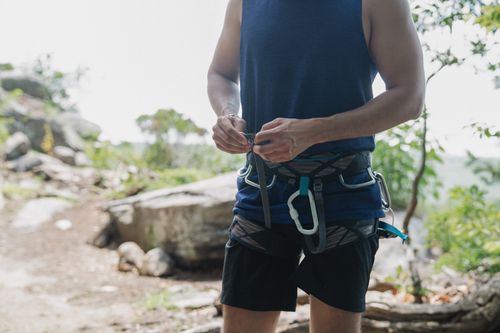 Free Outdoor scene of a man adjusting his climbing harness, prepping for adventure. Stock Photo