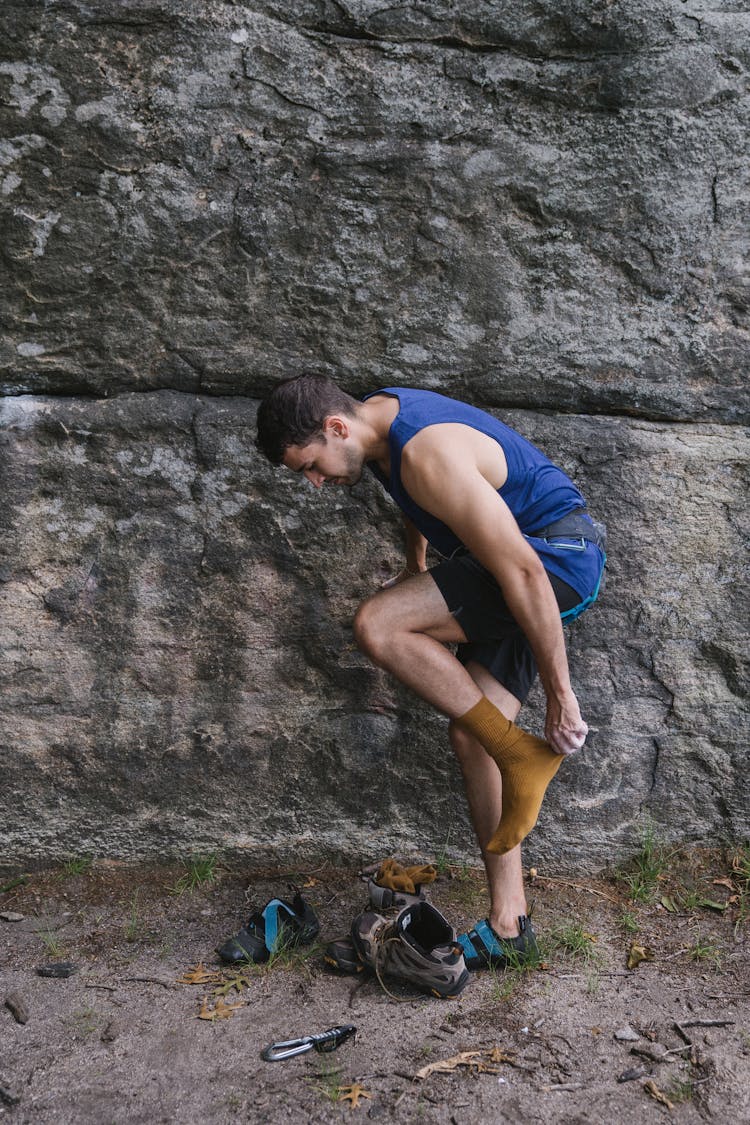 Climber Changing Shoes By A Rock