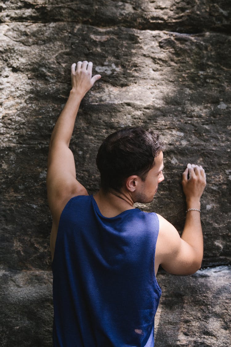 Back Of A Man Climbing A Stone Wall