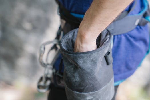 A climber's hand reaches into a chalk bag, highlighting climbing activity.