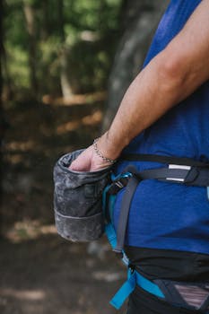 Male climber prepares by reaching into a chalk bag, highlighting his gear and focus