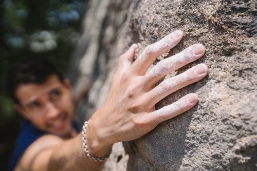Free Focused close-up of a man rock climbing with a chalked hand gripping rough surface. Stock Photo