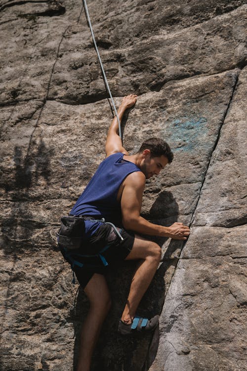 Person in Blue Tank Top Rock Climbing