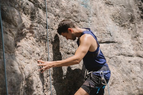 Man in Blue Tank Top Rock Climbing