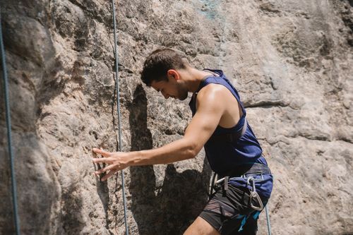 Free A male climber scales a rocky wall, showcasing strength and determination in a natural outdoor setting. Stock Photo