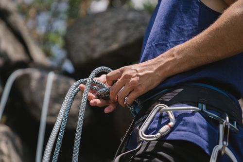 Free A rock climber tying knots and preparing safety gear for a climb outdoors. Stock Photo