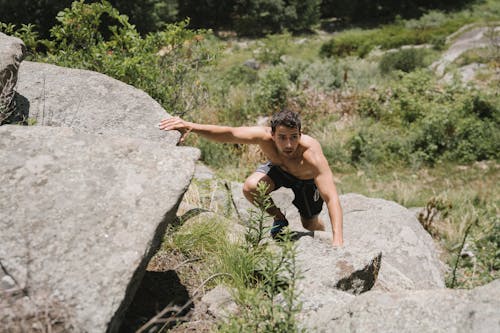 A Shirtless Man Climbing on Rocks