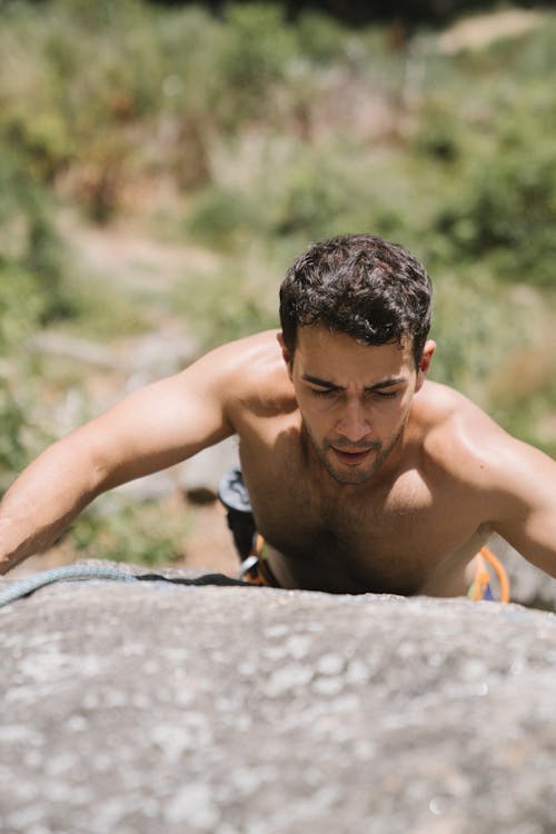Photo of a Shirtless Man Rock Climbing
