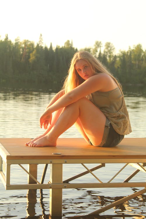 Woman in Brown Tank Top Sitting on Wooden Dock