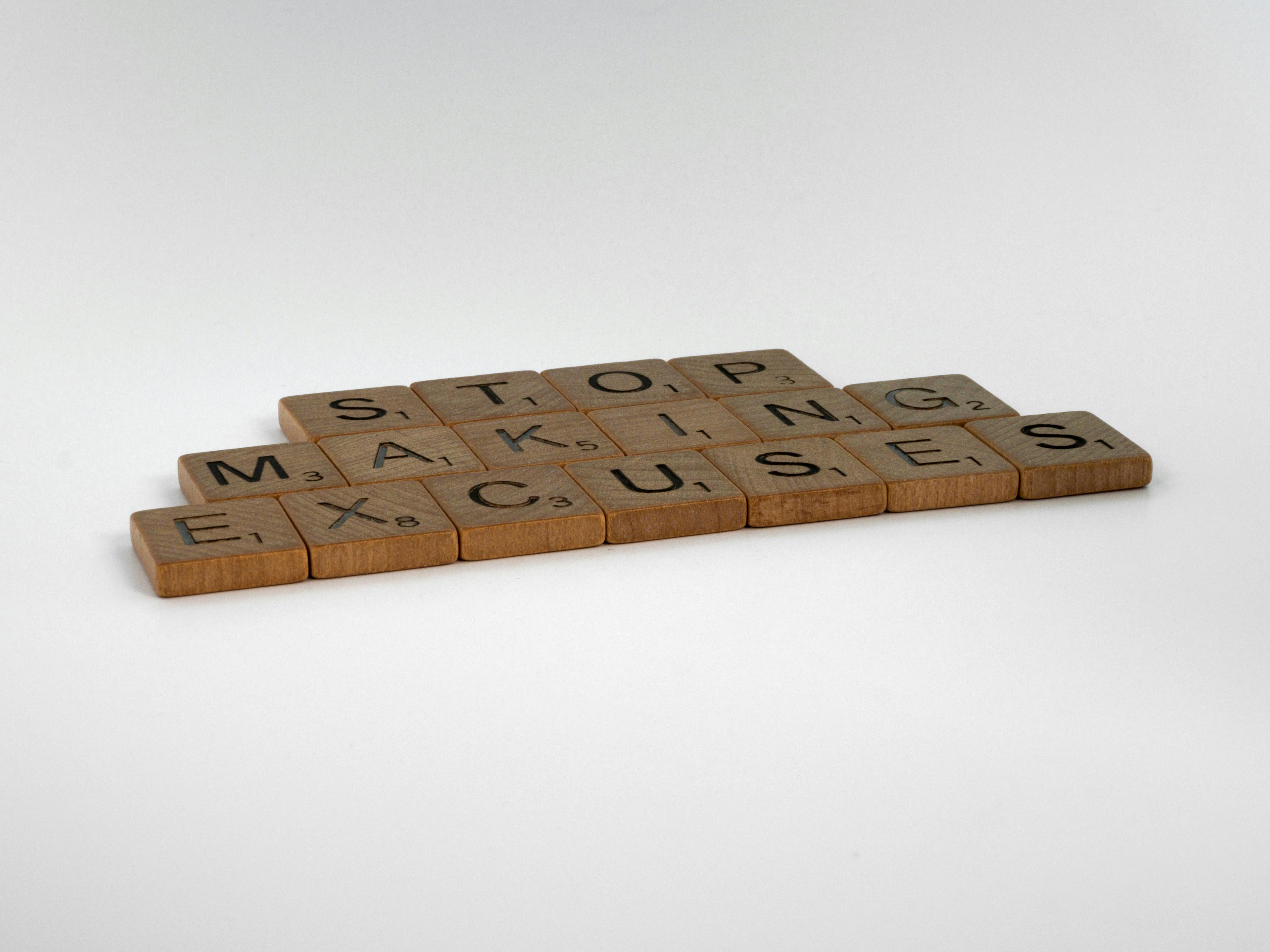 Inspirational phrase "Stop making excuses" crafted with wooden letter tiles.