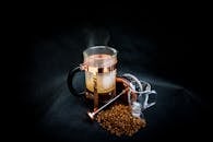 黑色背景上，一台时尚的法国印刷机印着热气腾腾的咖啡和豆子