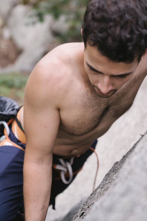 A Topless Man Climbing a Rock