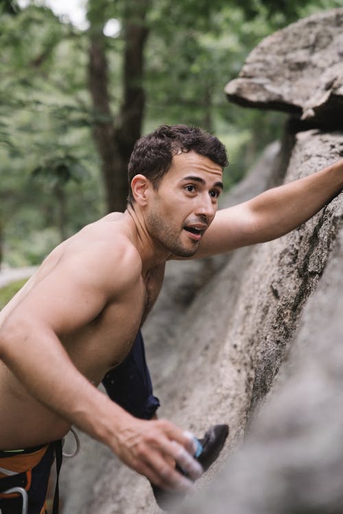 A Topless Man Climbing a Rock