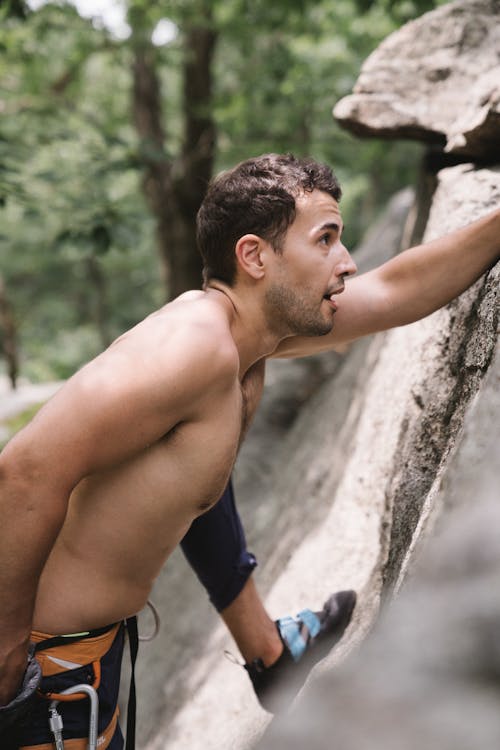 A Topless Man Climbing a Rock