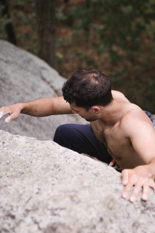 A Topless Man Climbing a Rock