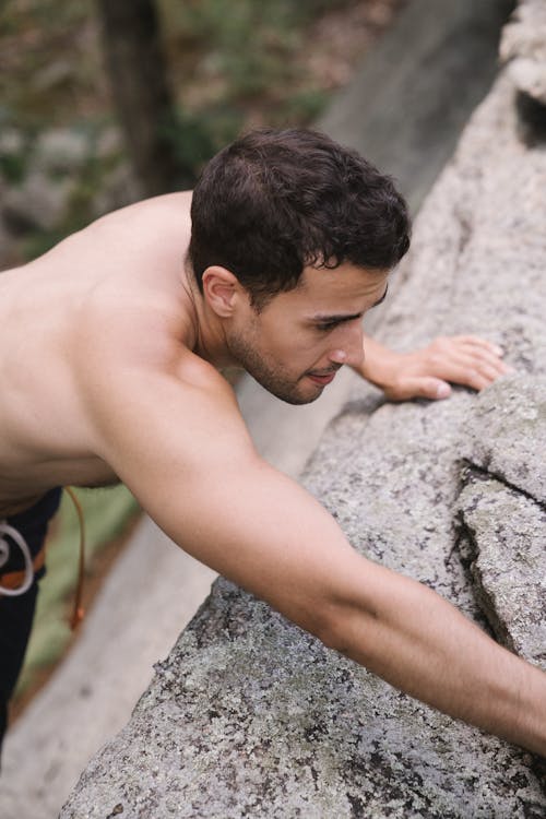 A Topless Man Climbing a Rock