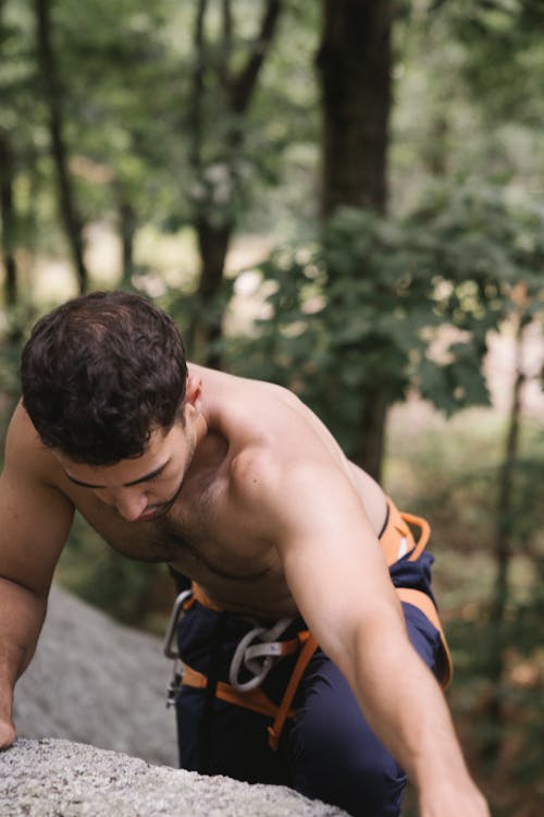 A Topless Man Climbing a Rock