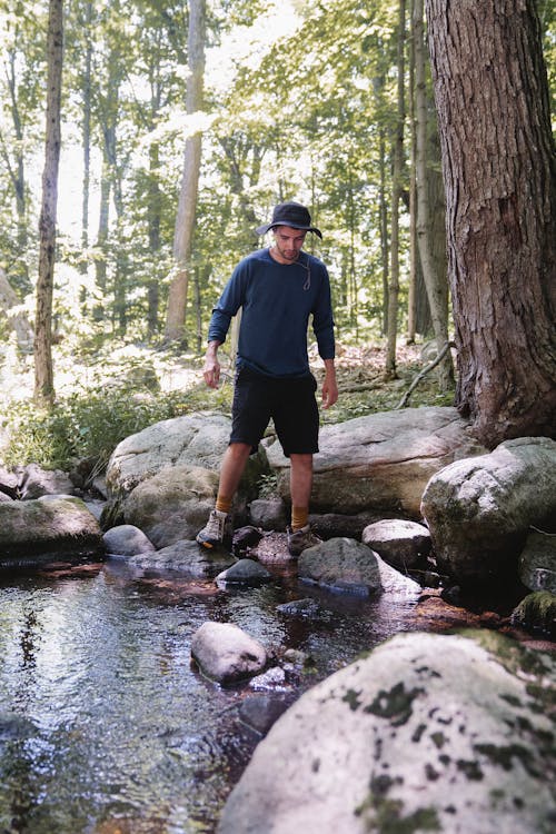 A Man Sanding on a River with Rocks 