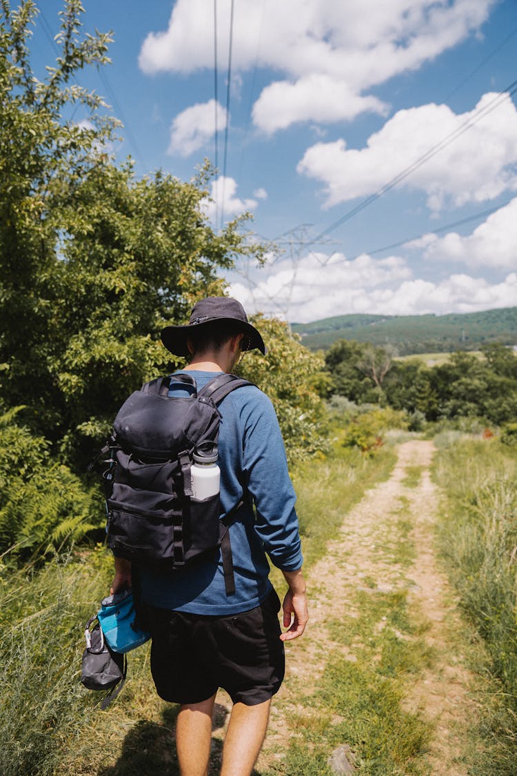 A Man With A Backpack Walking On A Pathway