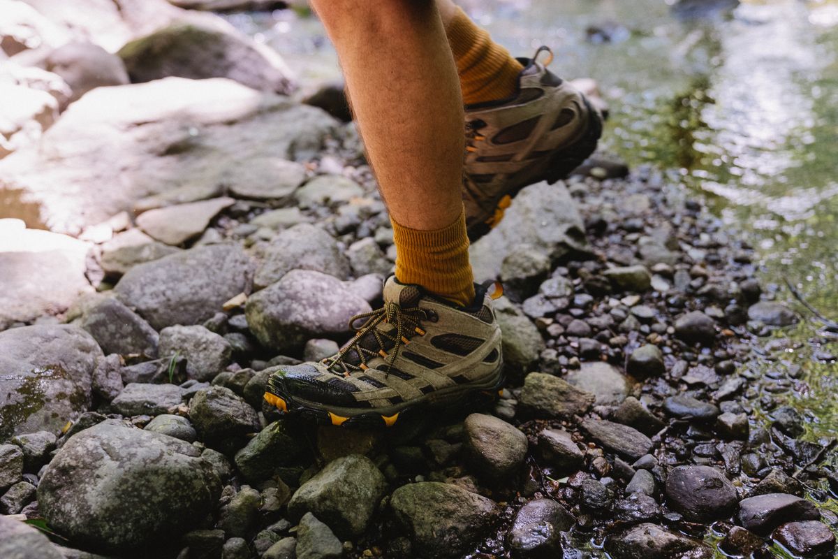 close up of feet stepping on rocks wearing supportive hiking socks