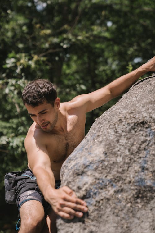 A Topless Man Climbing a Rock